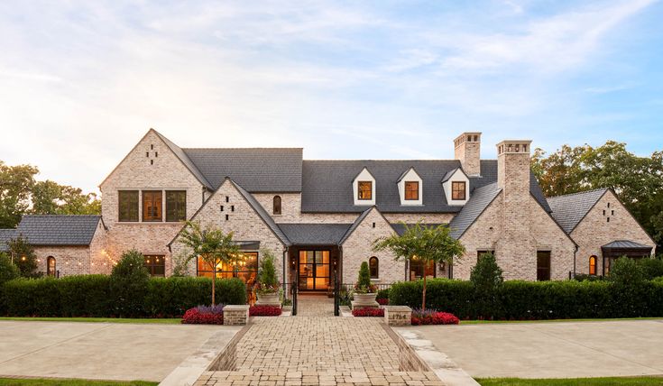 a large brick house with lots of trees and bushes around it's front entrance