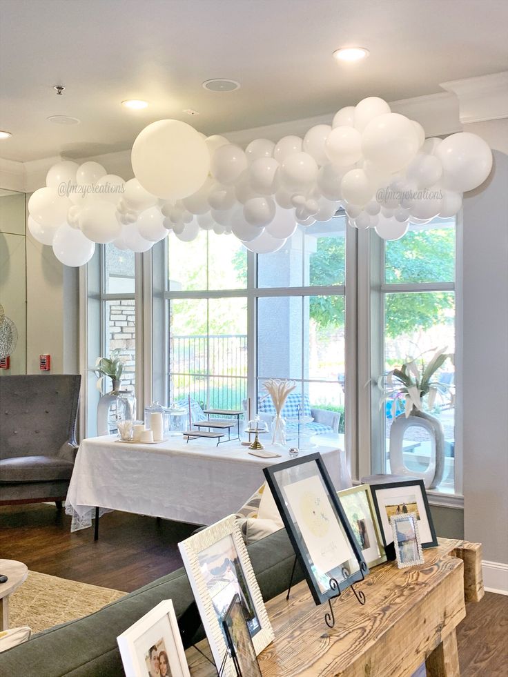 a living room filled with lots of furniture and balloons hanging from the ceiling above it