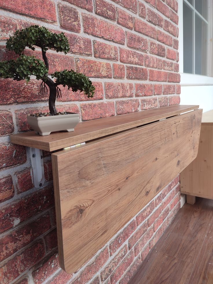 a bonsai tree is placed on the ledge of a brick wall in front of a window