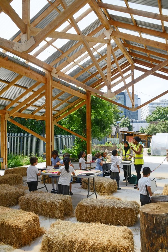 children are gathered around hay bales under a wooden structure