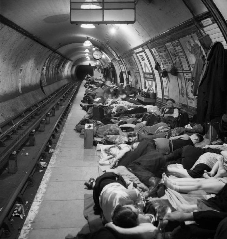 there are many people sleeping on the train tracks in this subway tunnel, and one person is taking a photo