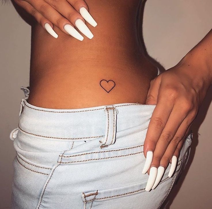 a woman's stomach with a small heart tattoo on it