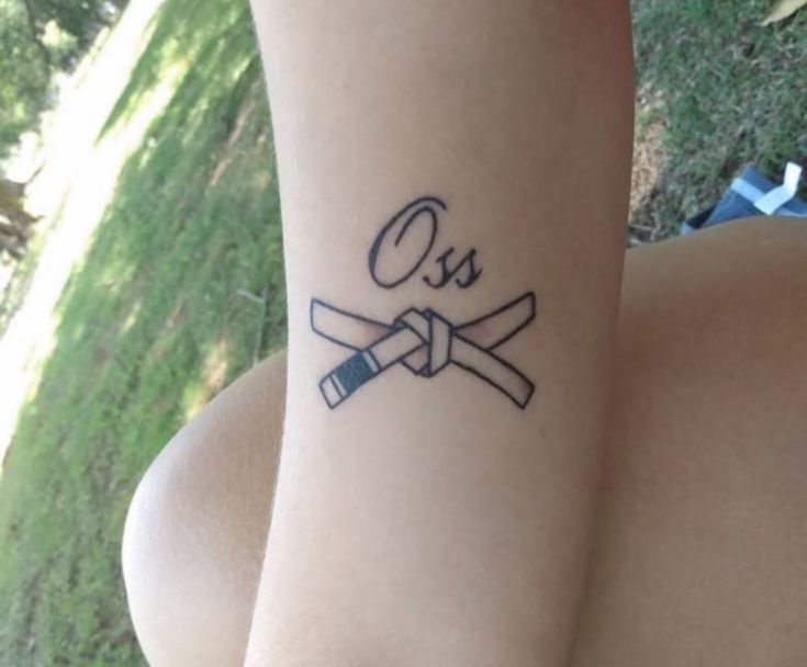 a person with a tattoo on their arm that says oes and two crossed swords