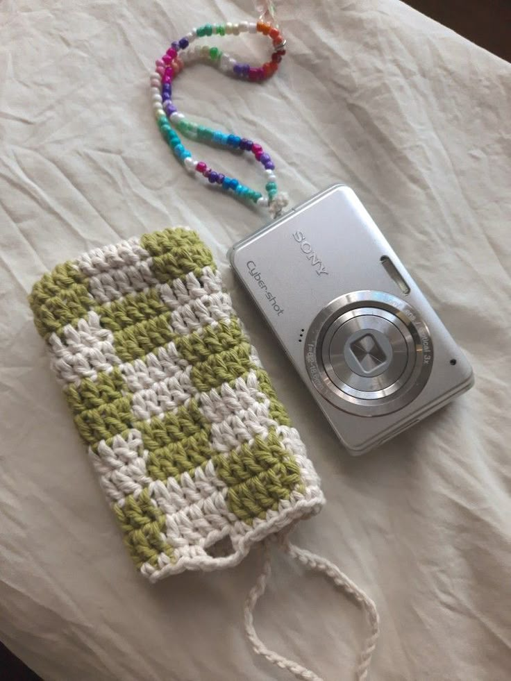 a camera is laying next to a crocheted purse