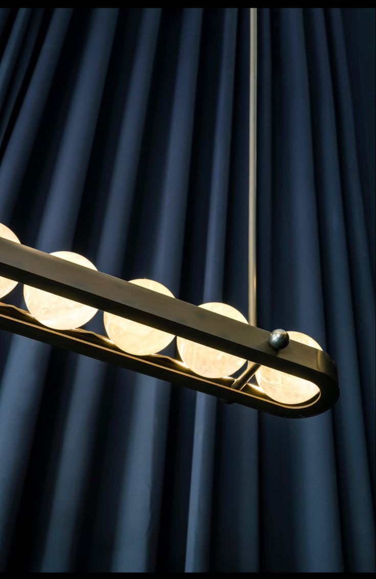 a light fixture hanging from the ceiling in front of blue curtained walls and drapes