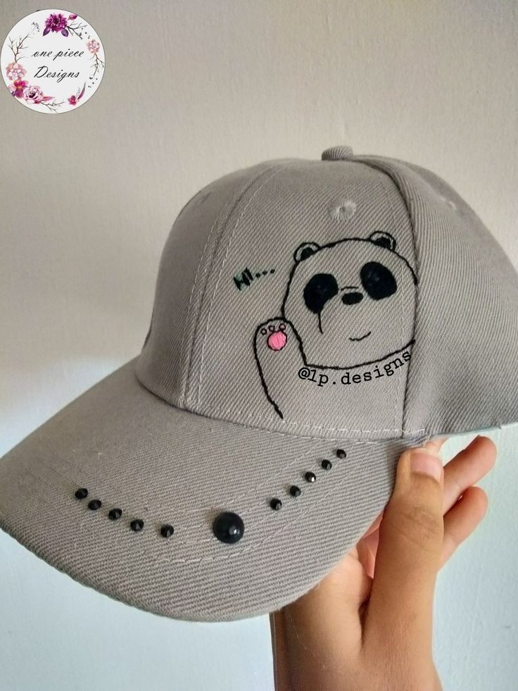 a person holding up a baseball cap with a panda bear on it's side