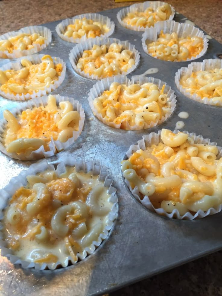 nine cupcakes with macaroni and cheese in them on a baking tray