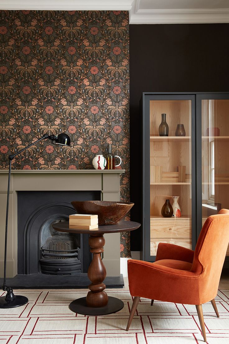 a living room filled with furniture and a fire place in front of a wallpapered fireplace