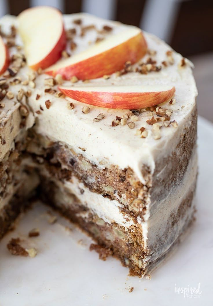 there is a cake that has apples on top and nuts on the side, with one slice cut out