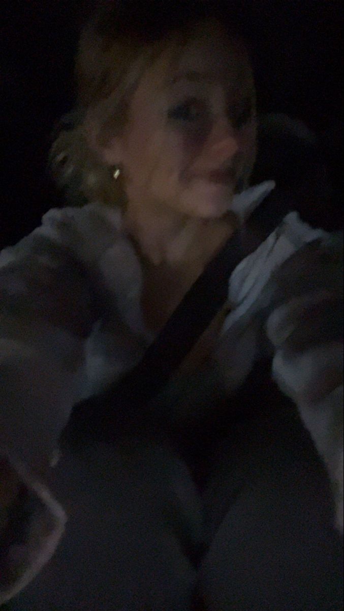 a woman sitting in the back seat of a car at night with her head turned to the side