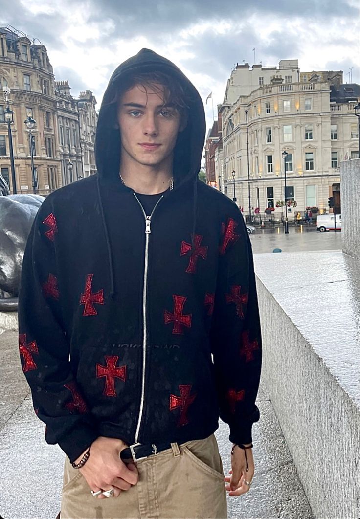 a young man wearing a black hoodie with red crosses on it