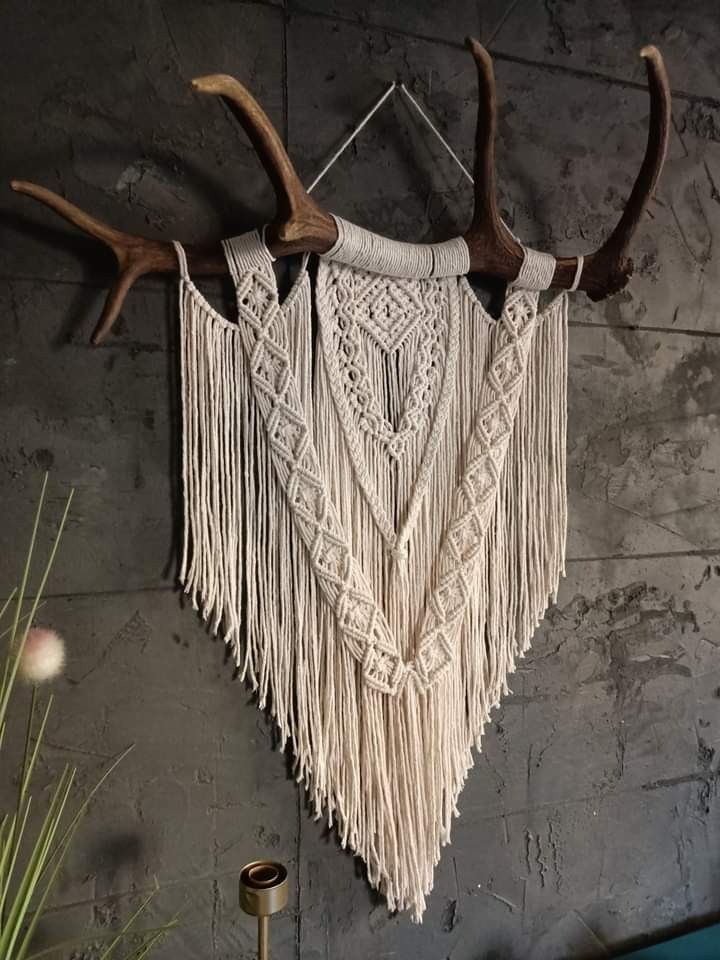 an antler's head hanging on the wall next to a vase with flowers in it