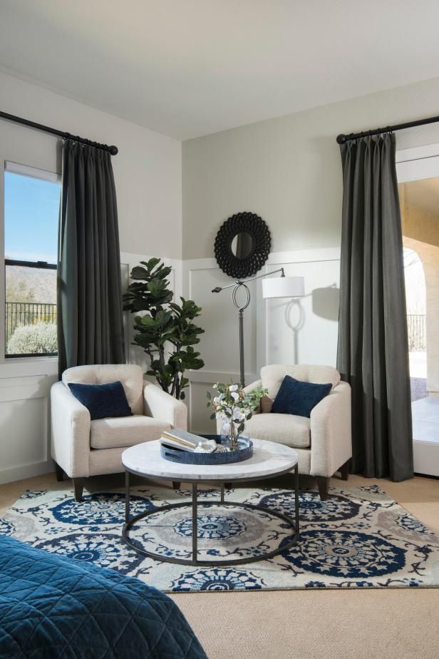 a living room with two chairs and a coffee table in front of a window that has curtains on it