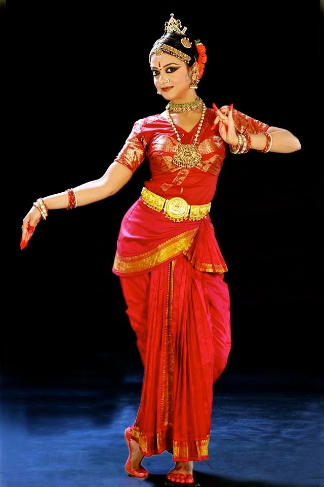 a woman dressed in red and gold dancing