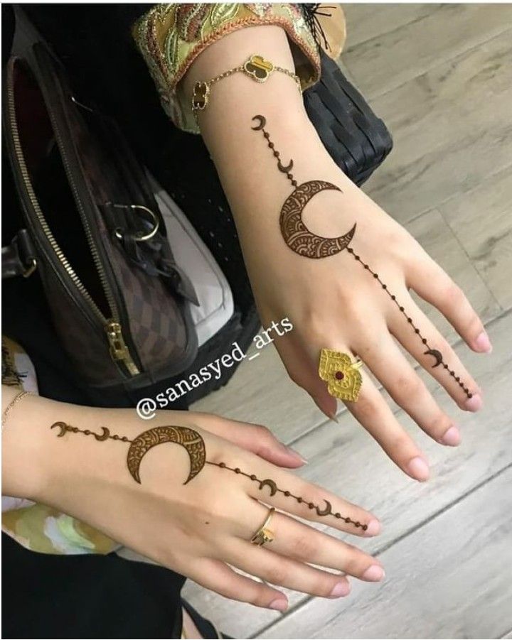 two girls with henna tattoos on their hands, one is holding the other hand