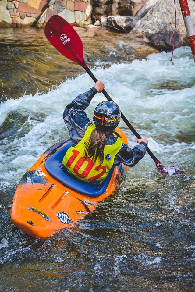 a person in an orange kayak paddling down a river