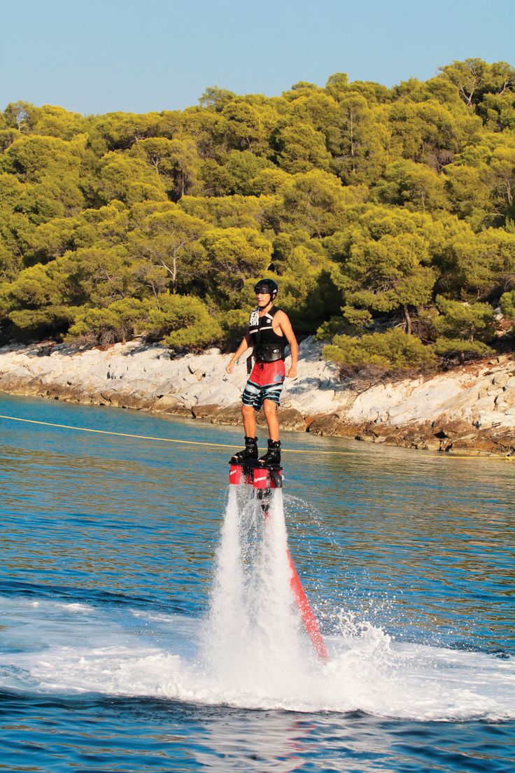 a man on water skis in the ocean with trees in the backgroud