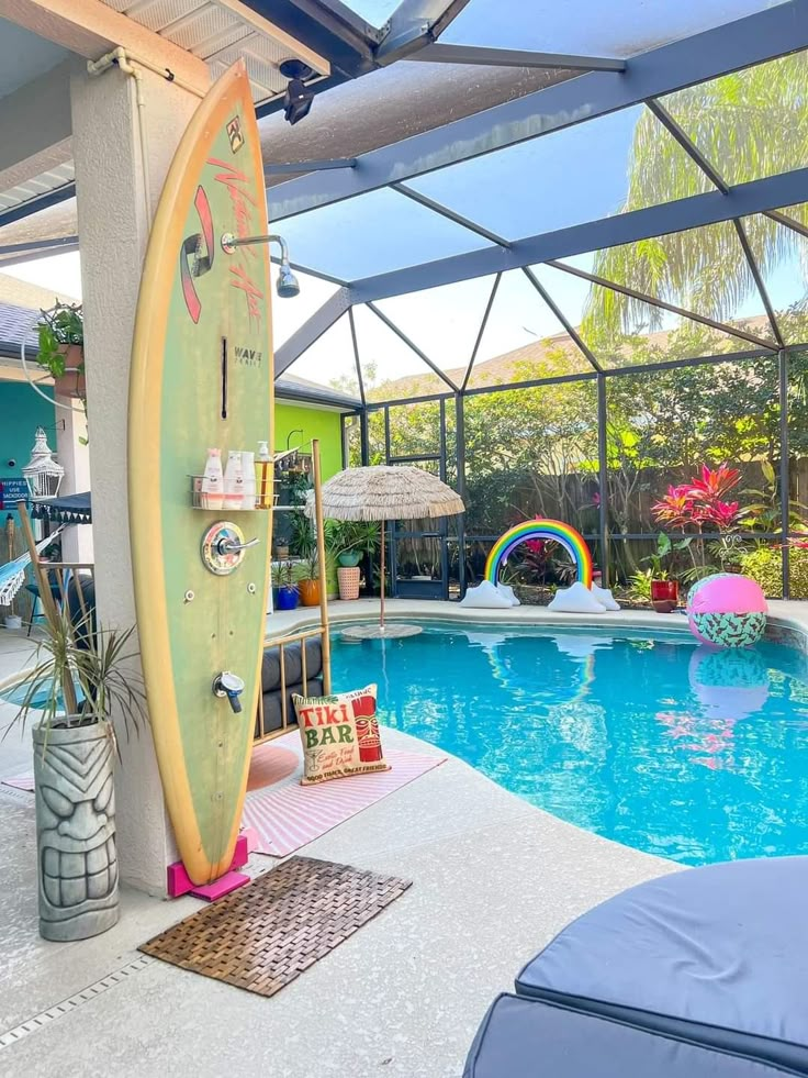 a surfboard is propped up against the wall next to a swimming pool in a backyard