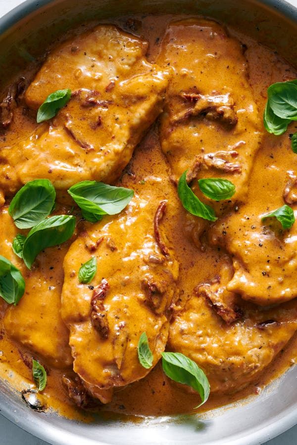 a pan filled with meat covered in gravy and garnished with green leaves