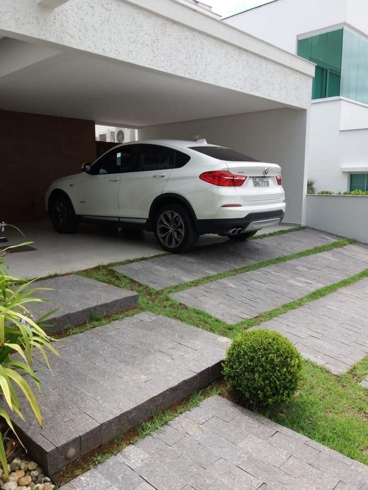 a white car is parked in front of a garage with steps leading up to it