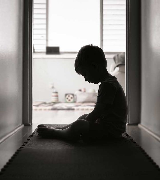 a little boy sitting on the floor in front of a door