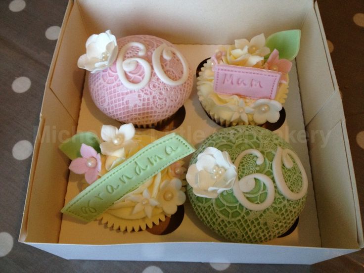 three decorated cupcakes in a box on a table