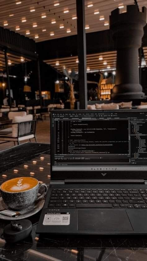 an open laptop computer sitting on top of a table next to a cup of coffee