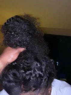 the back of a man's head with curly hair in it and his hand on top of his head