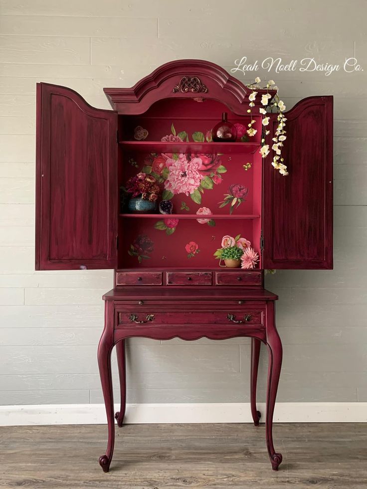 a red china cabinet with flowers painted on it