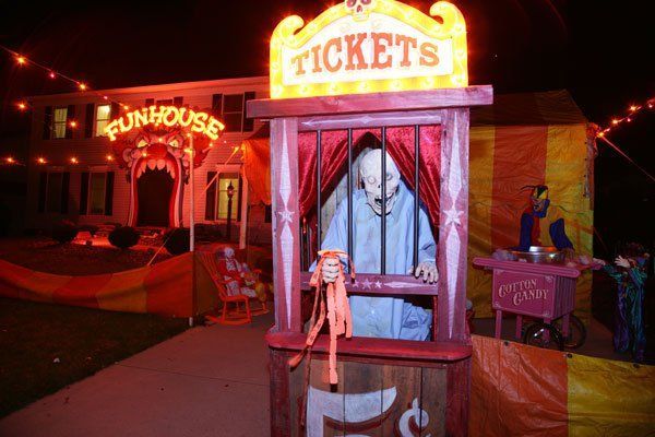 a creepy puppet is sitting in the middle of a booth at an amusement park with lights strung from it's sides