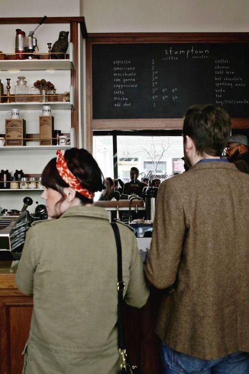 two people standing at a counter in a coffee shop