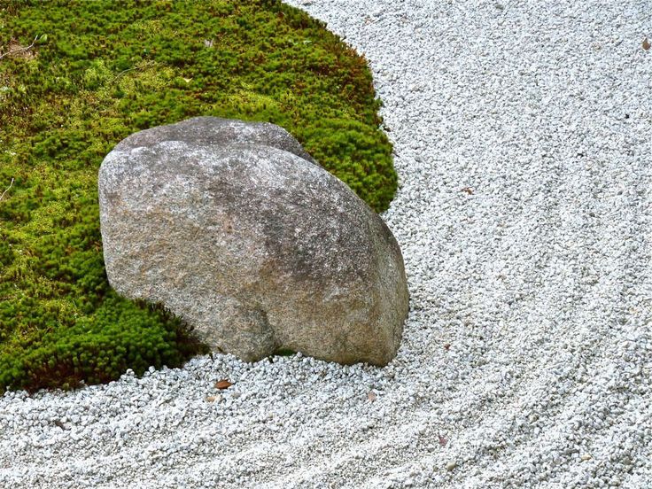 a large rock sitting on top of a gravel covered ground