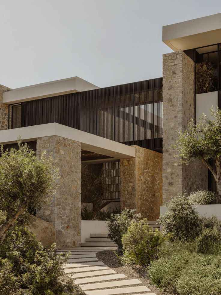 an exterior view of a modern house with stone steps leading to the front door and side entrance