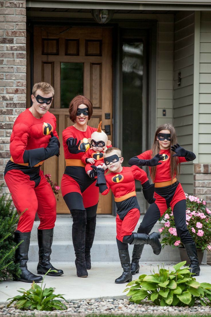 a group of people in costumes standing on the front steps of a house with their arms around each other