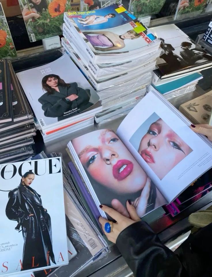 many magazines are stacked on top of each other in front of a woman's face