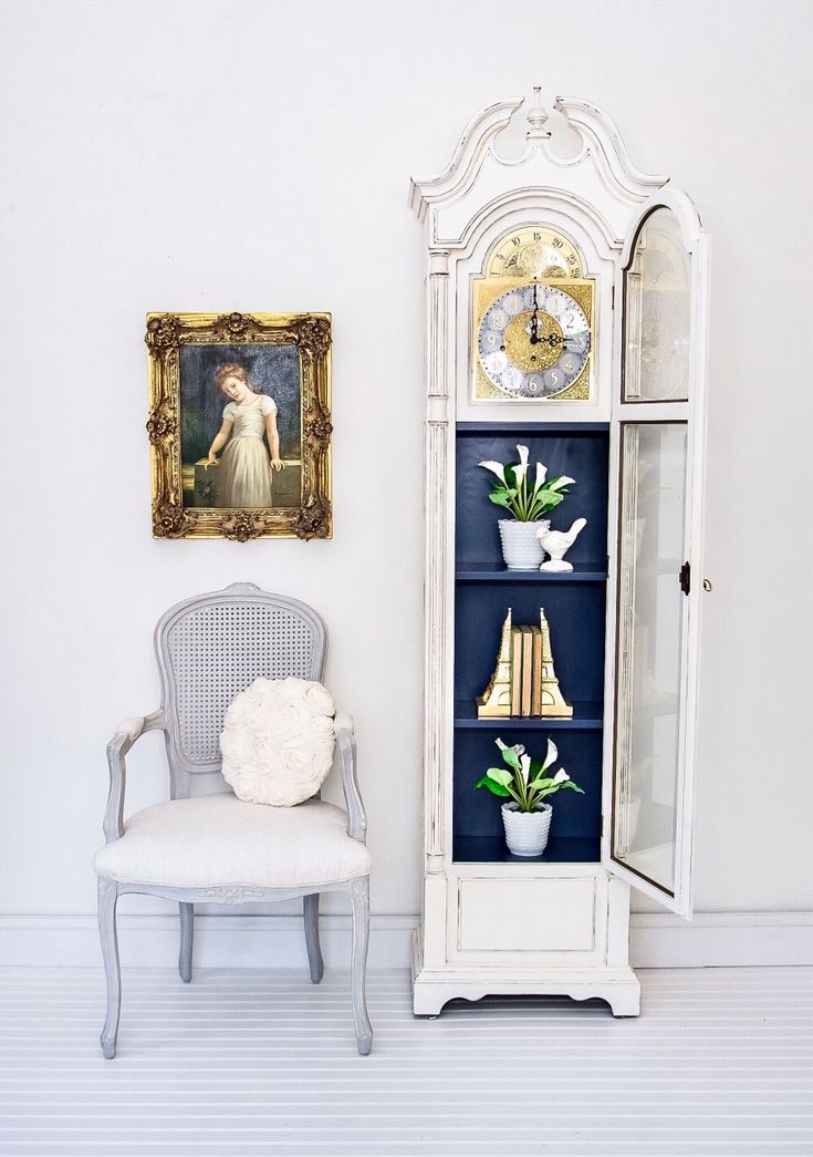 a white chair sitting in front of a tall cabinet with pictures on it's sides