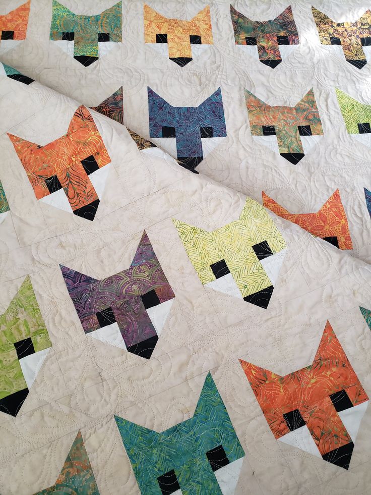 a quilt made to look like cats with different colors