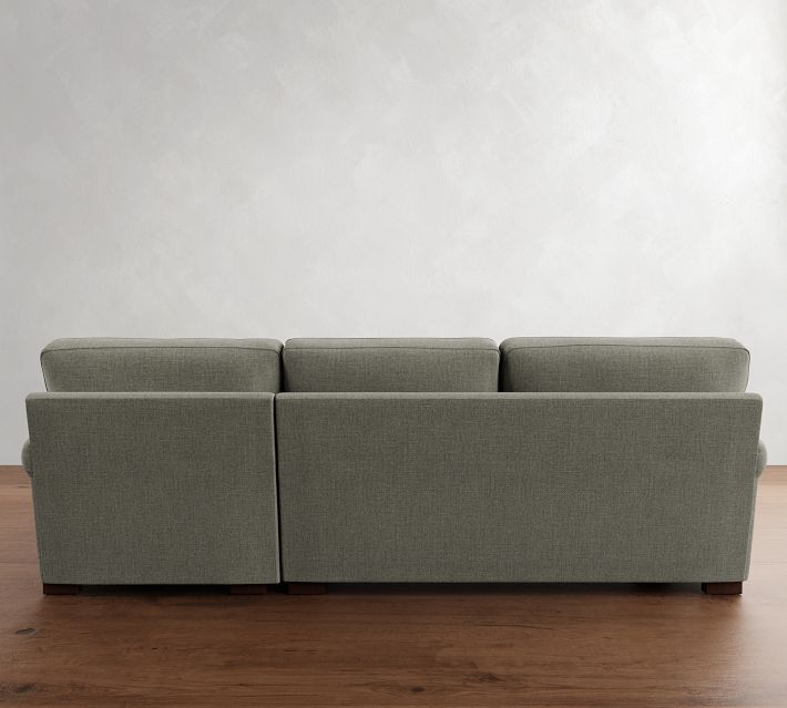 a gray couch sitting on top of a wooden floor next to a white wall in an empty room