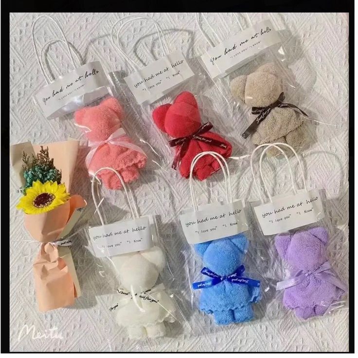 several small bags with flowers in them sitting on a white tableclothed surface and tied to twine