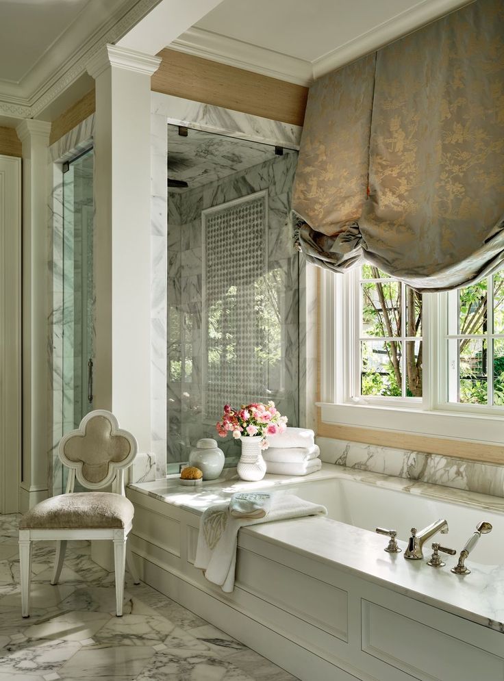 a bath room with a tub and a chair next to a flower vase on the counter