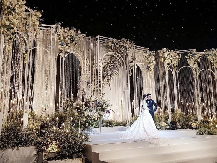 a bride and groom standing in front of an elaborately decorated stage