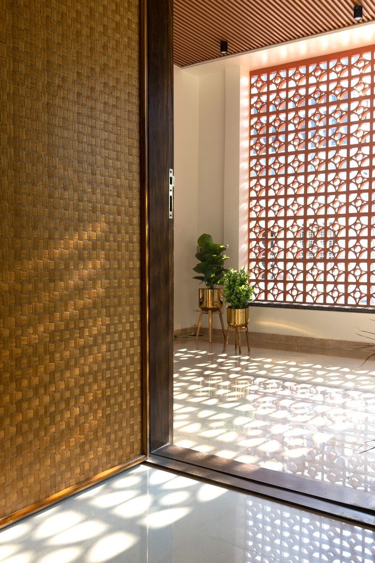 an open door leading into a room with a plant in the corner and sunlight streaming through it