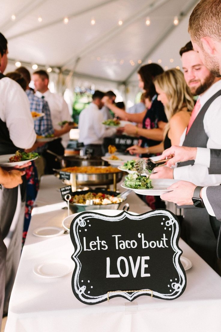 people standing around a table with food on it and a sign that says let's taco bout love