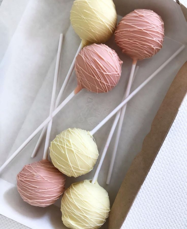 four pink and white cake pops in a box