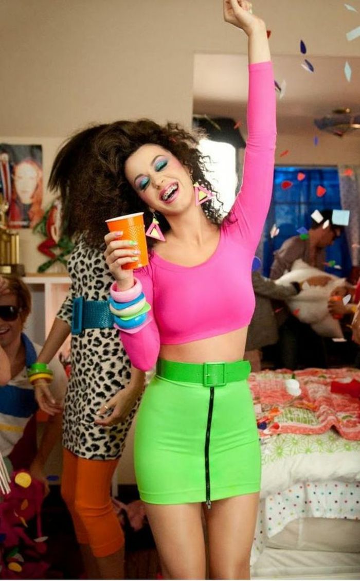 a woman in pink shirt and green pants holding a cup with confetti on it