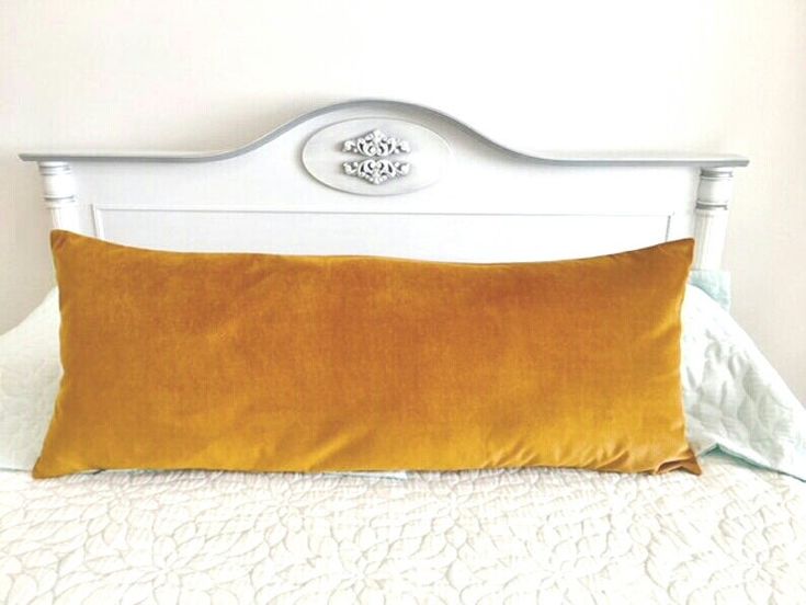 a white headboard with an orange pillow on it