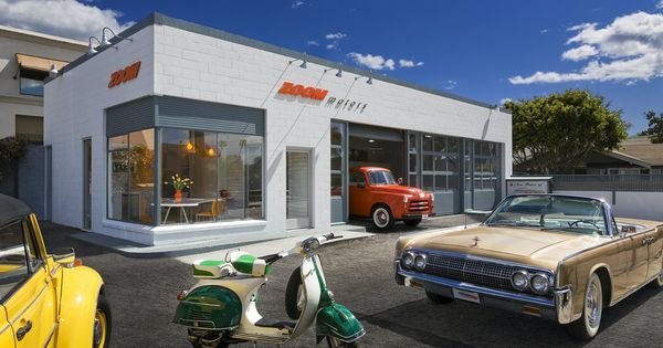 two old cars and a scooter parked in front of a building with an awning