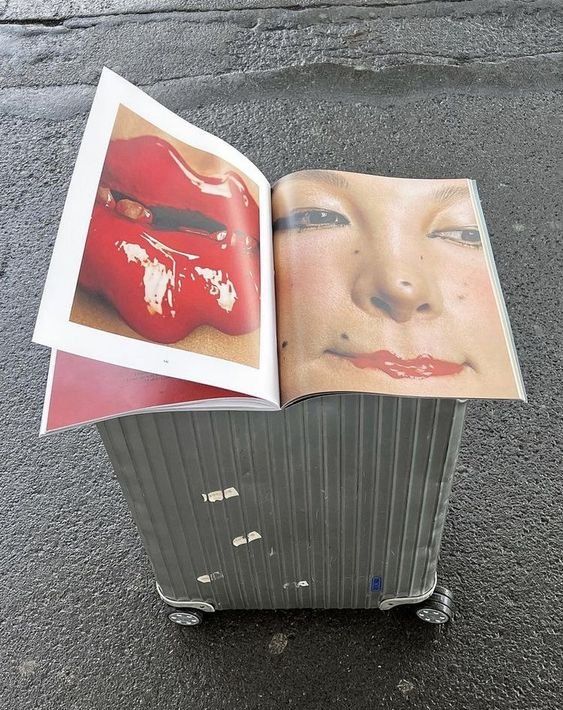 an open book with pictures on it sitting on top of a luggage cart in the street