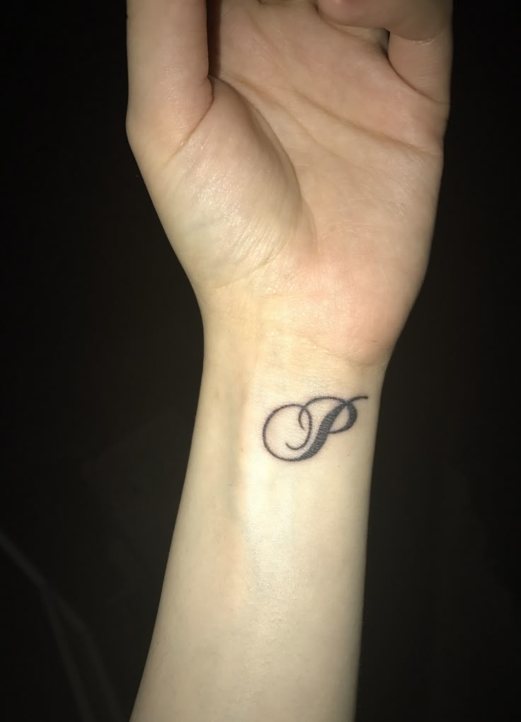 a woman's wrist tattoo with the letter p on it