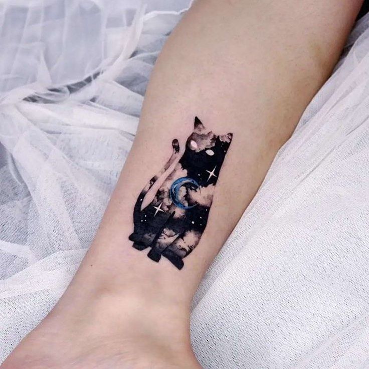 a black and white cat tattoo on the left inner arm, with space in the background